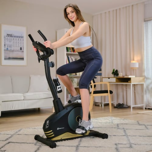 Une femme sportive et souriante fait du vélo d'appartement classique