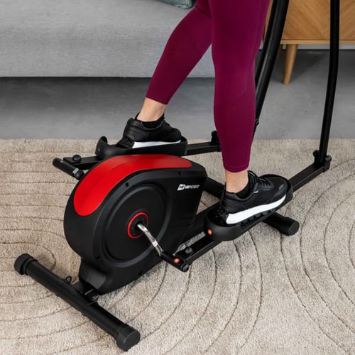Gros plan sur le corps noir et rouge d'un vélo elliptique de marque Hop-Sport, posé dans un salon.