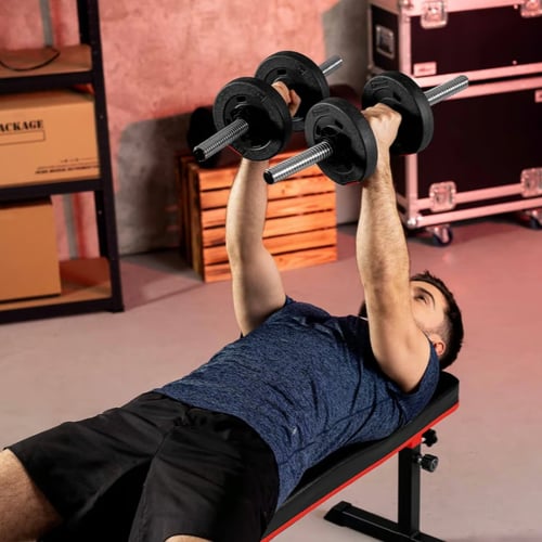 Un homme fait des extensions triceps couchés avec des haltères sur un banc de musculation.