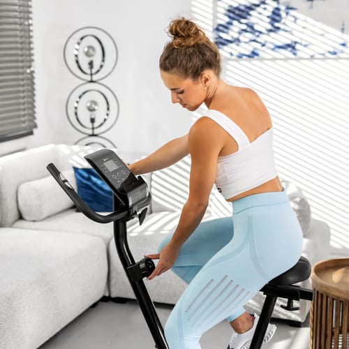 Une femme en tenue de sport règle un vélo d'appartement.