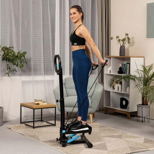 Une femme souriante se tient debout sur un stepper en tirant les poignées vers l'arrière