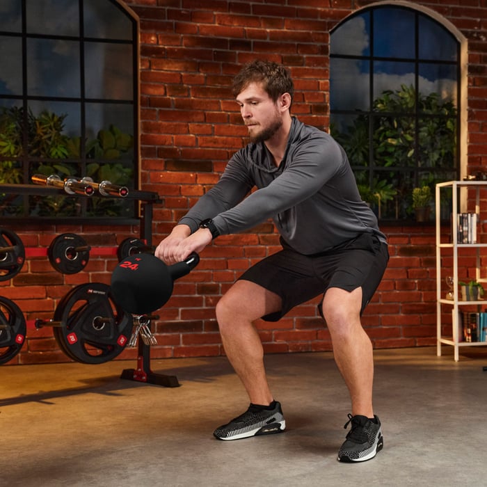 Homme s’entraînant avec kettlebells Hop-Sport à domicile